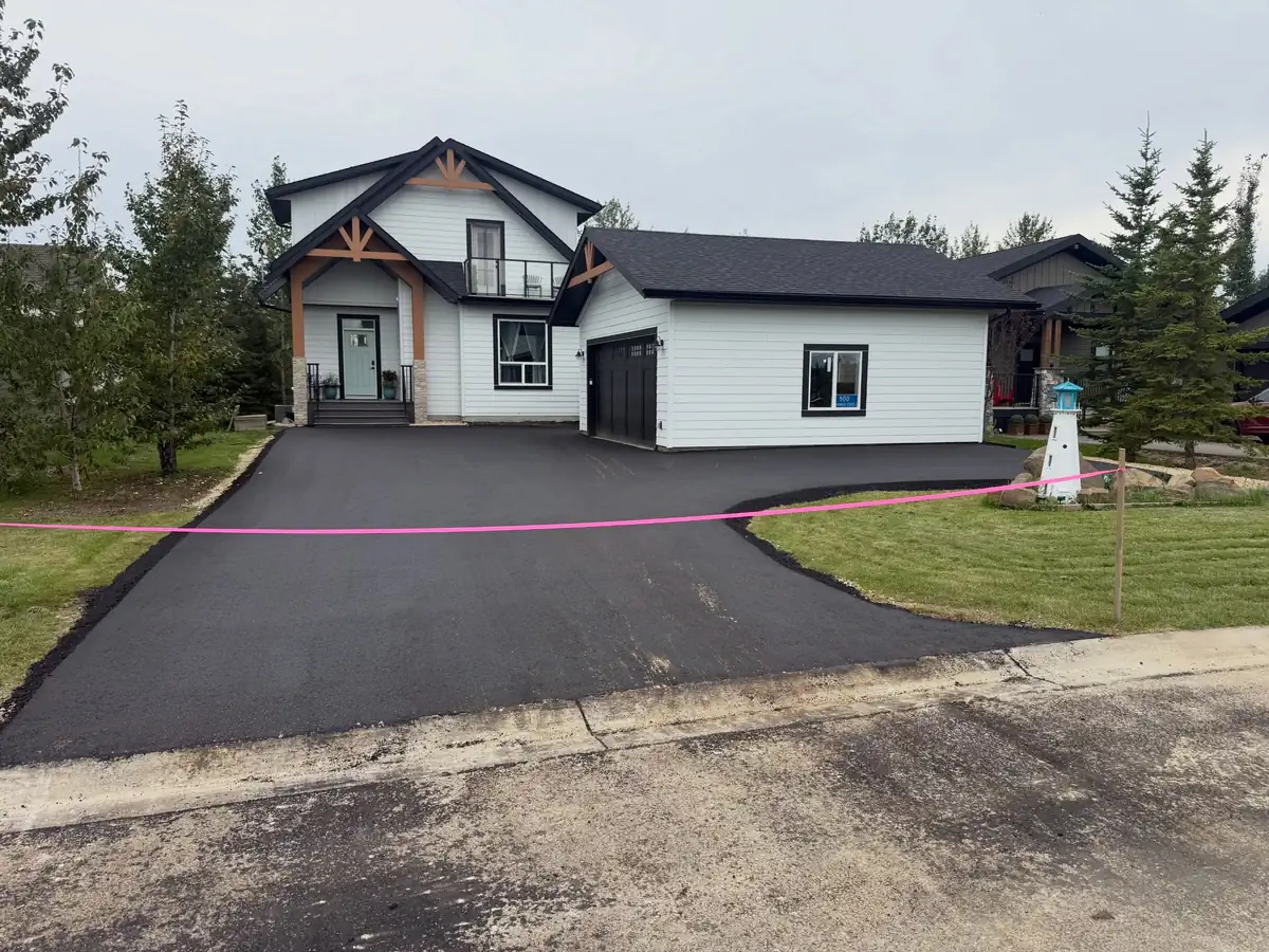 Curved asphalt driveway paved for a newly built home with a three-car garage
